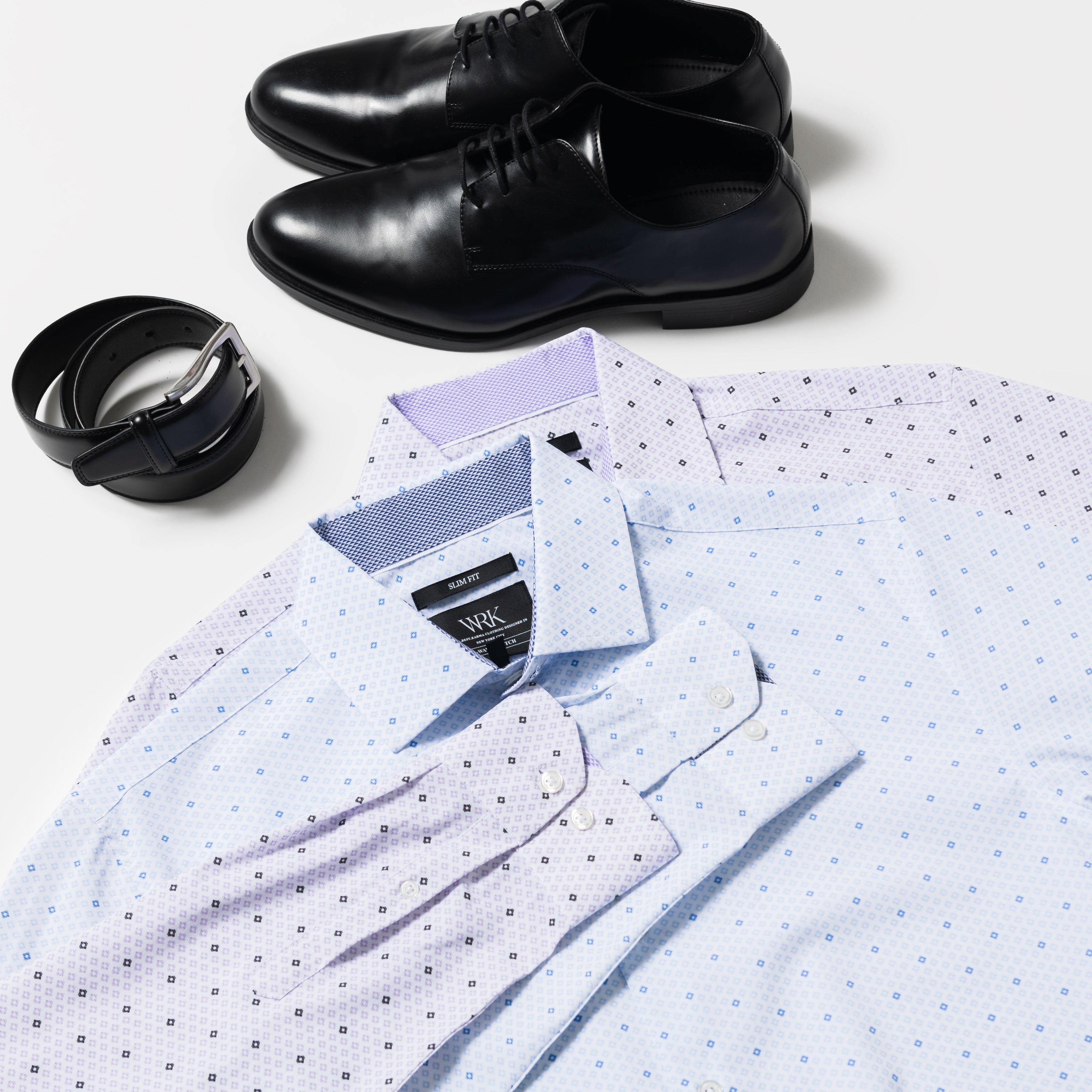 Folded white shirt with blue dots, black shoes, and a black container on a light gray background