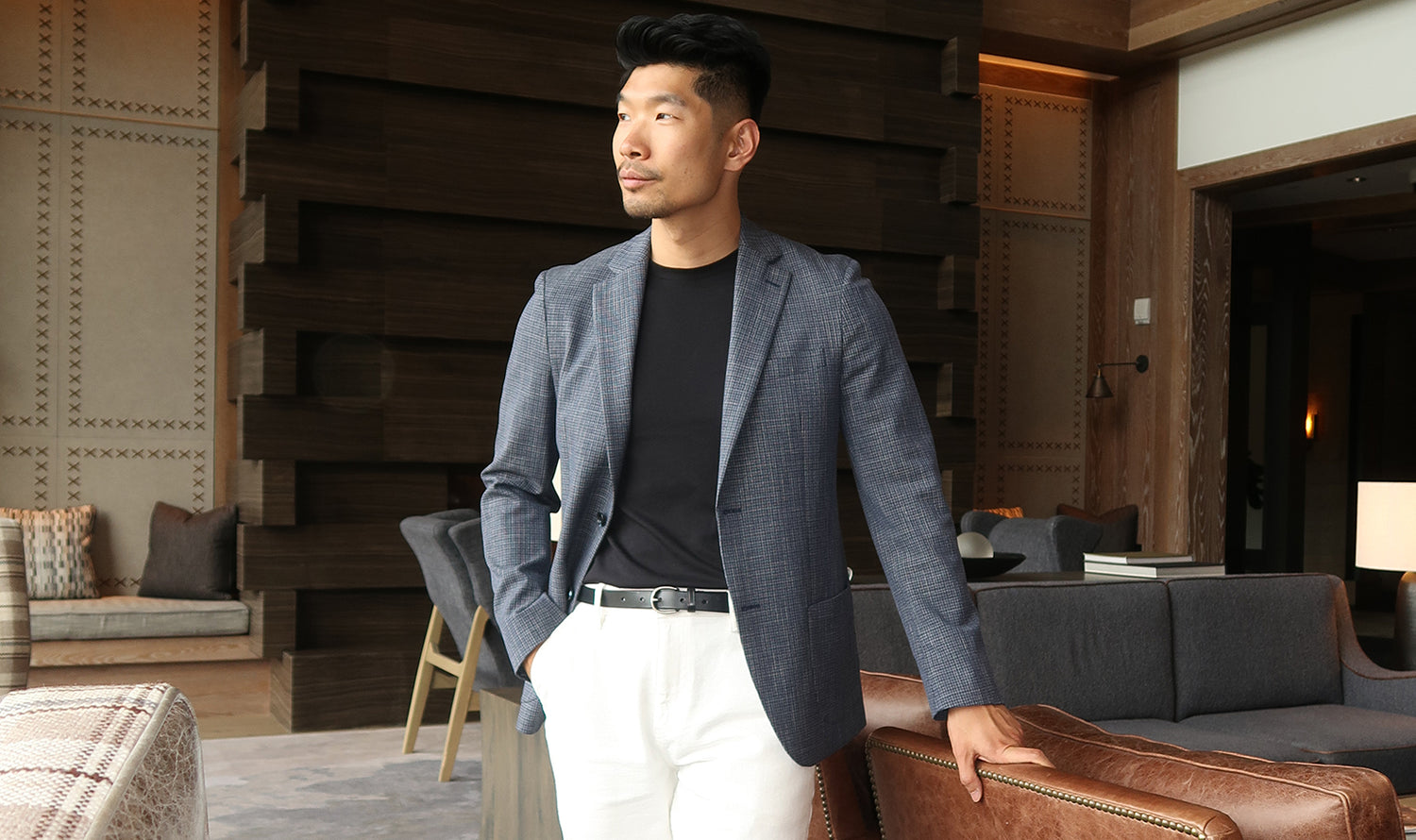 Man in a stylish outfit standing in a modern living room.